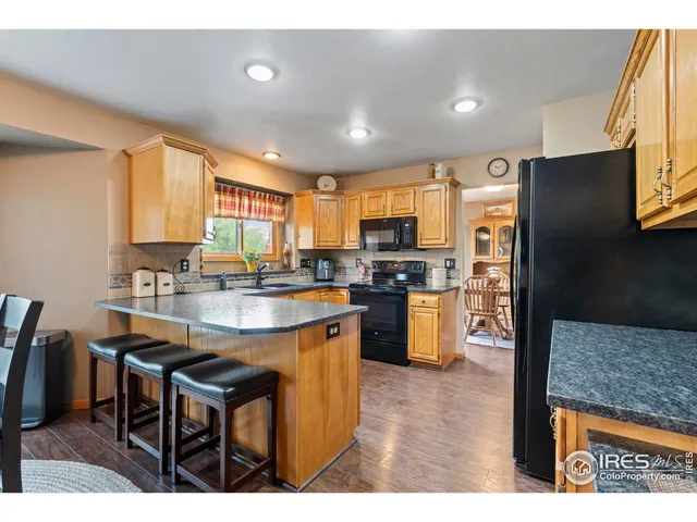 a kitchen with stainless steel appliances granite countertop a refrigerator a sink a stove a dining table and chairs