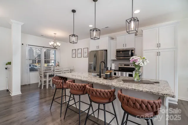 a kitchen with kitchen island granite countertop a stove a sink a dining table and chairs