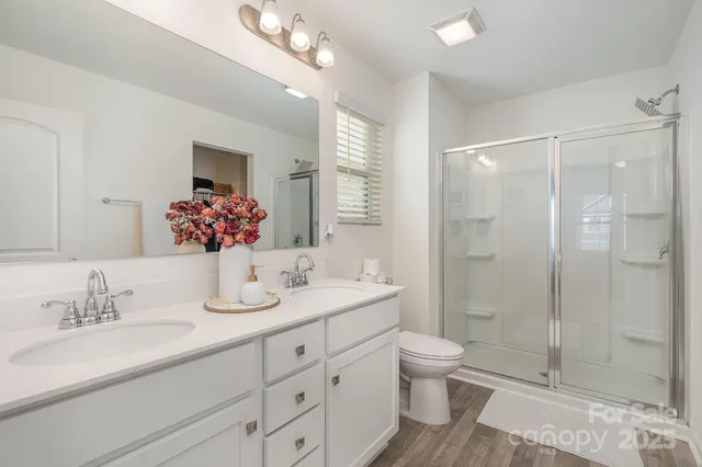 a bathroom with a granite countertop sink a toilet a shower and a mirror