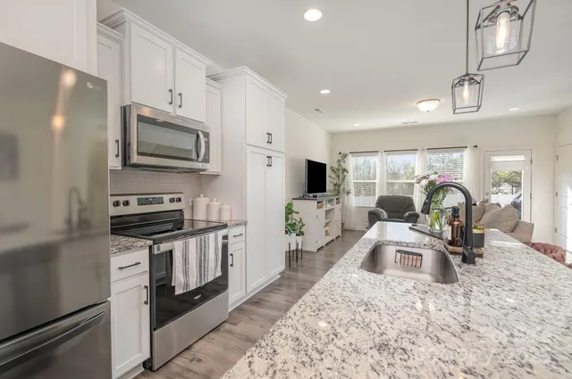 a kitchen with stainless steel appliances granite countertop a sink stove microwave and refrigerator