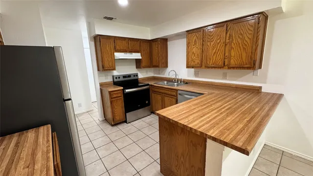 a kitchen with granite countertop a sink stove and refrigerator