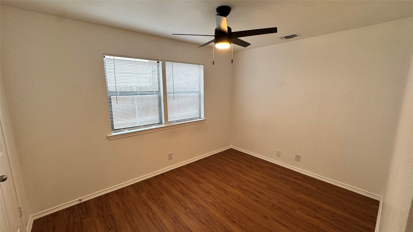 1304 Conway Drive, Unit B San Marcos, TX 78666 - Photo 9 of 16 an empty room with wooden floor chandelier fan and windows