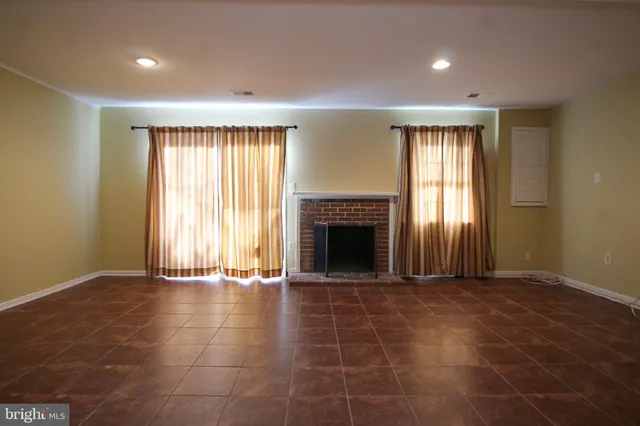 a view of an empty room with a window and fireplace