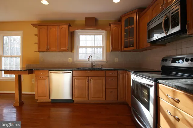 a kitchen with stainless steel appliances granite countertop a stove a sink and a microwave