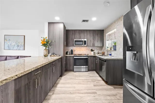 a large kitchen with stainless steel appliances kitchen island a sink stove and refrigerator