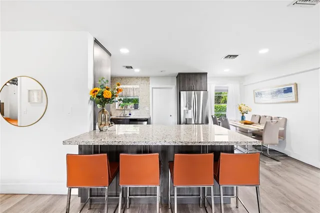 a kitchen with stainless steel appliances granite countertop a kitchen island a table and chairs