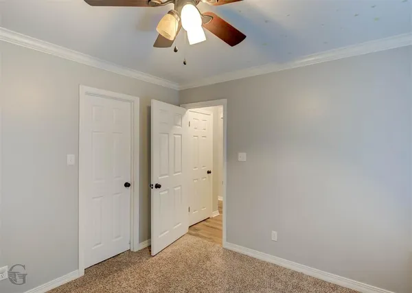 an empty room with a chandelier fan and closet