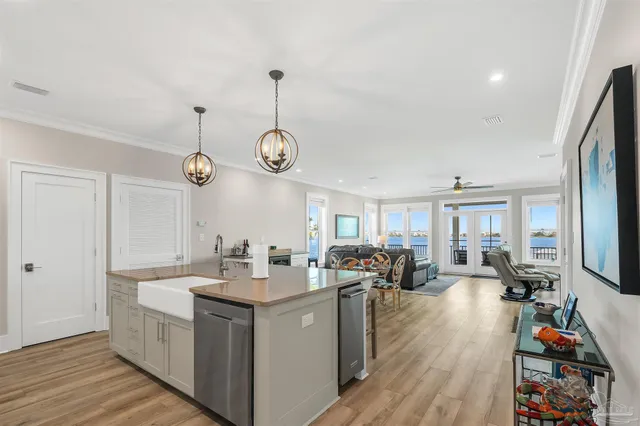 a kitchen with a refrigerator a stove a sink dishwasher a dining table and chairs with wooden floor