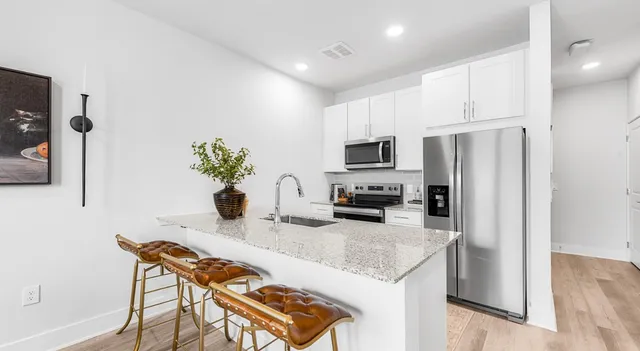a kitchen with a refrigerator a stove a sink and chairs