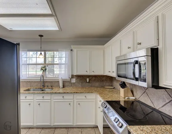 a kitchen with granite countertop a sink stove and cabinets