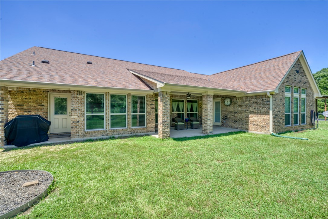 9945 Oxford Cemetery Road Madisonville, TX 77864 - Photo 27 of 42 Rear view of house featuring a patio, a shingled roof, brick siding, and a yard