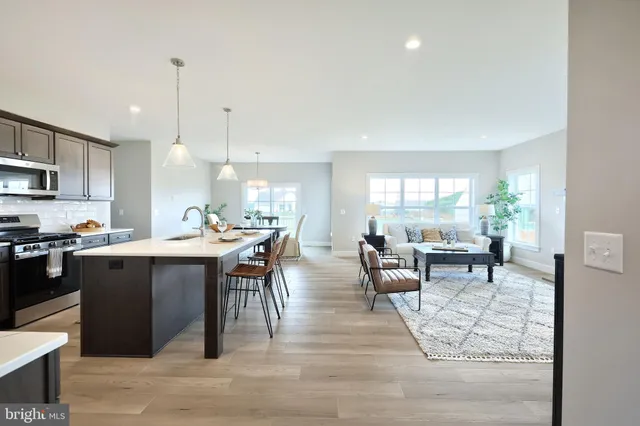 a kitchen with stainless steel appliances granite countertop a stove top oven a sink a dining table and chairs with wooden floor