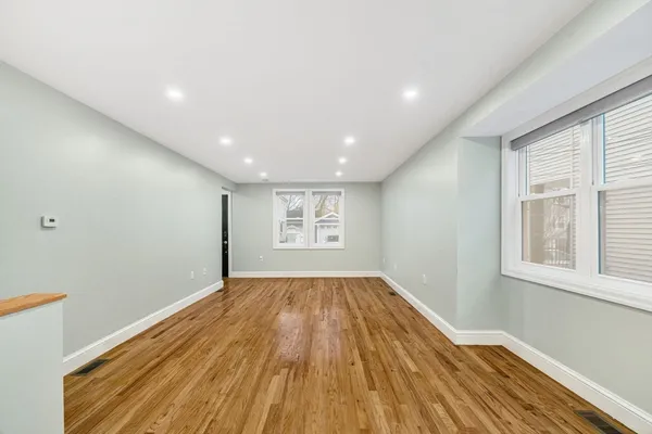 a view of empty room with wooden floor and fan