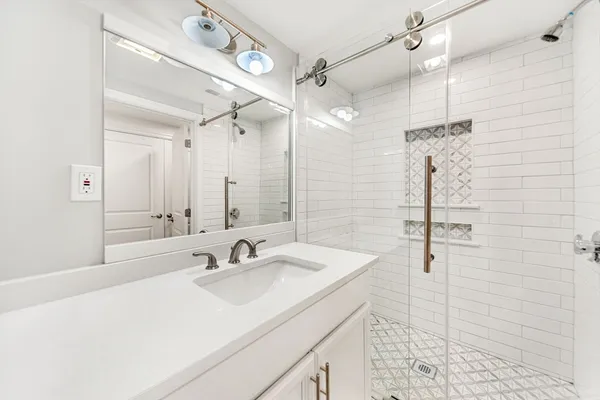 a bathroom with a sink shower and a mirror