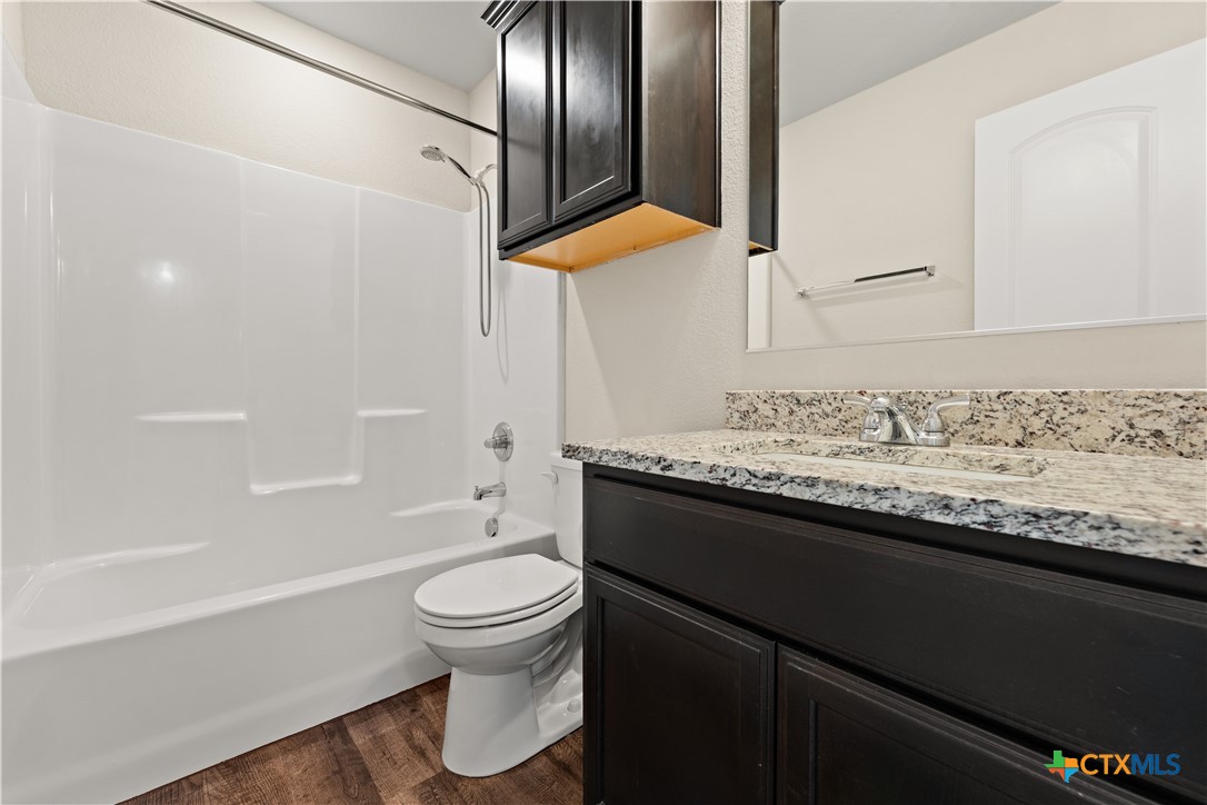 4124 Riata Ranch Road Waco, TX 76705 - Photo 21 of 26 a bathroom with a granite countertop sink toilet and shower