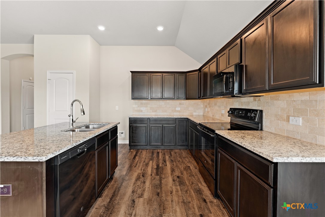 4124 Riata Ranch Road Waco, TX 76705 - Photo 10 of 26 a kitchen with stainless steel appliances granite countertop a sink stove and cabinets