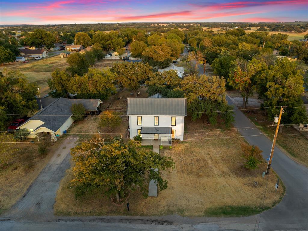 202 North Kickapoo Street Lipan, TX 76462 - Photo 35 of 38 White two-story residence with a dark metal roof and covered porch