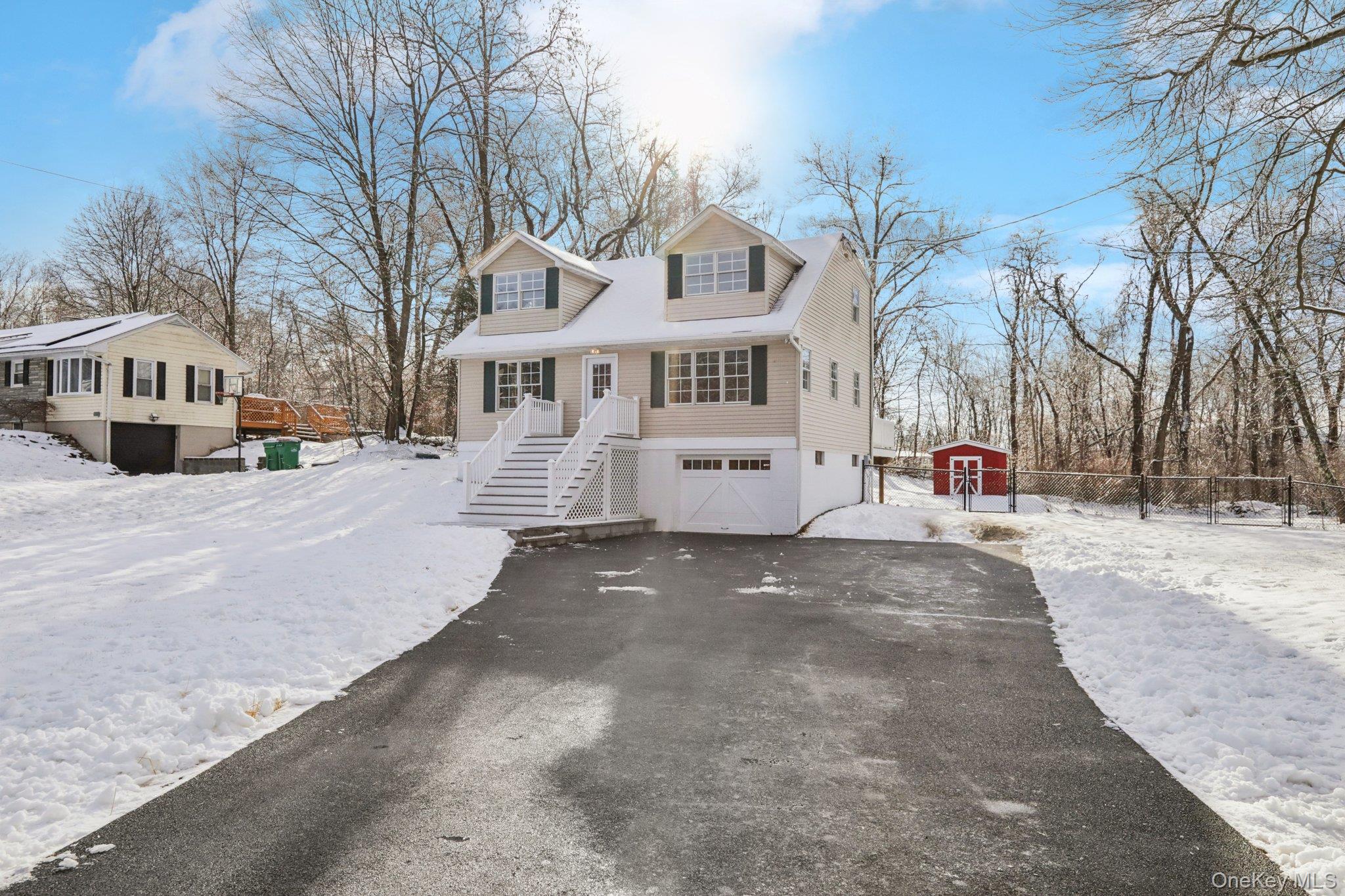 View of front of home with new asphalt driveway, a new garage door, and an outdoor shed