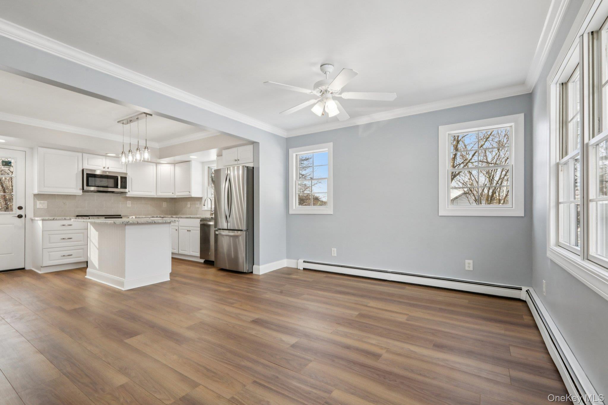 95 Smithtown Road Fishkill, NY 12524 - Photo 12 of 50 Kitchen and dining room featuring a baseboard radiator, appliances with stainless steel finishes, crown molding, decorative light fixtures, and white cabinetry.