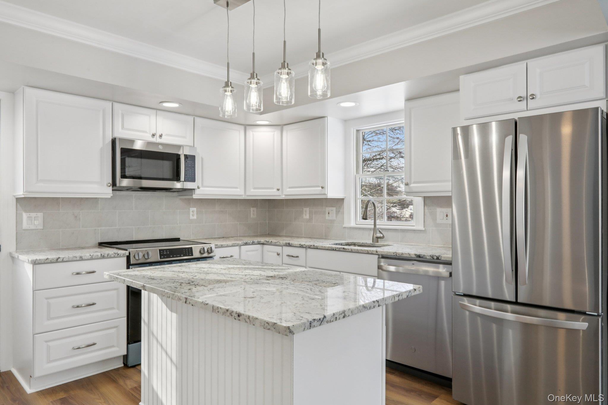 95 Smithtown Road Fishkill, NY 12524 - Photo 15 of 50 Kitchen featuring appliances with stainless steel finishes, light quartzite countertops, white cabinetry, decorative backsplash, and crown molding