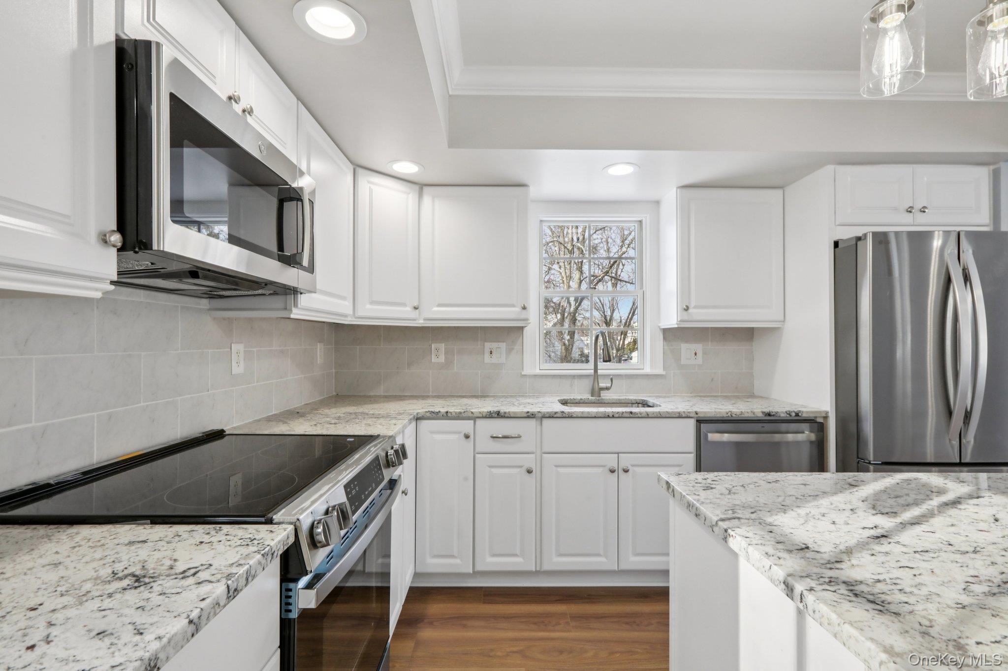 95 Smithtown Road Fishkill, NY 12524 - Photo 18 of 50 Kitchen with stainless steel appliances, light quartzite counters, dark wood finished floors, crown molding, and white cabinetry
