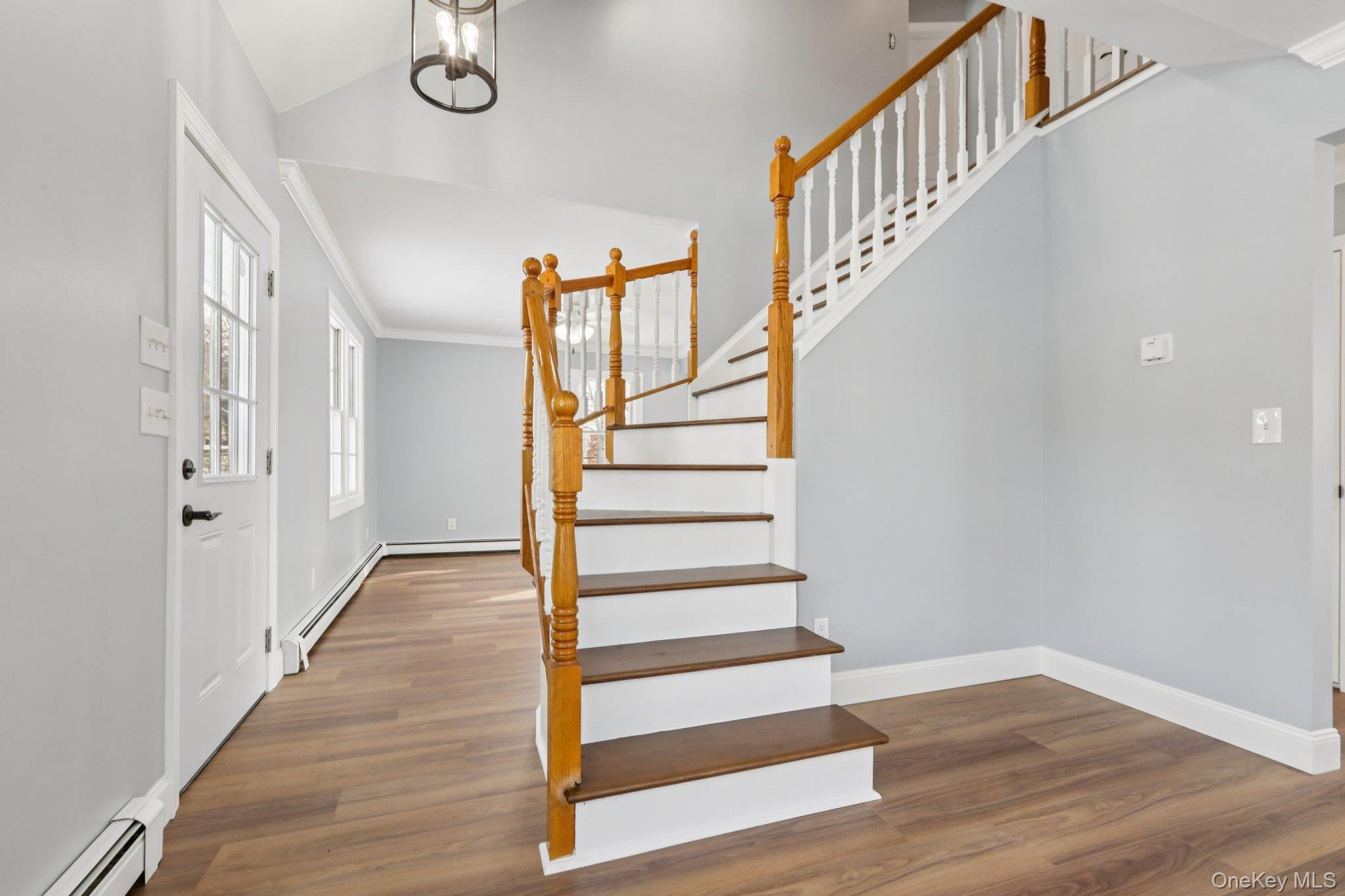 95 Smithtown Road Fishkill, NY 12524 - Photo 4 of 50 Entryway featuring ornamental molding, a baseboard radiator, dark waterproof flooring, vaulted ceiling, and stairway