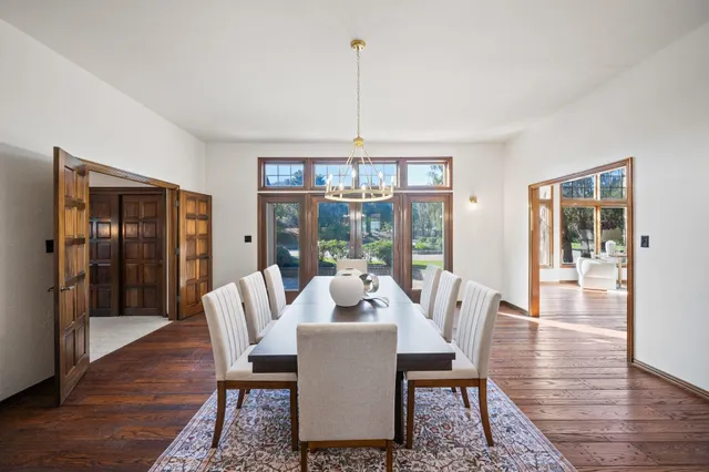 a dining room with furniture wooden floor a rug a potted plant and a chandelier