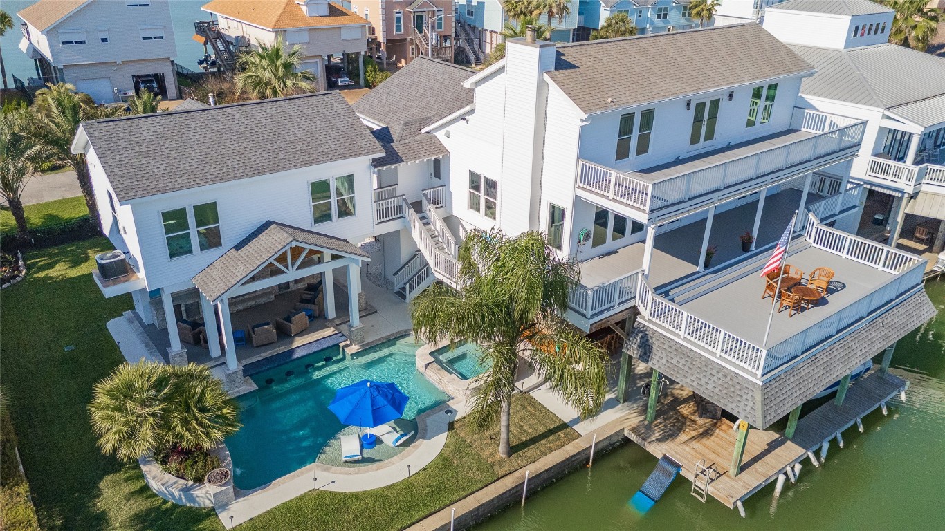 242 Isles End Road Tiki Island, TX 77554 - Photo 1 of 50 This sweeping, aerial view of Isles End highlights the waterfront property in all its splendor. To the right is the main house with multiple decks and boathouse, complete with a custom Tiki Bar, pizza kitchen, boat slip, swimming ladder, and dog ramp so they can climb safely to land after a nice swim in the canal. To the left is the guesthouse and resort style pool with sun deck and spa.