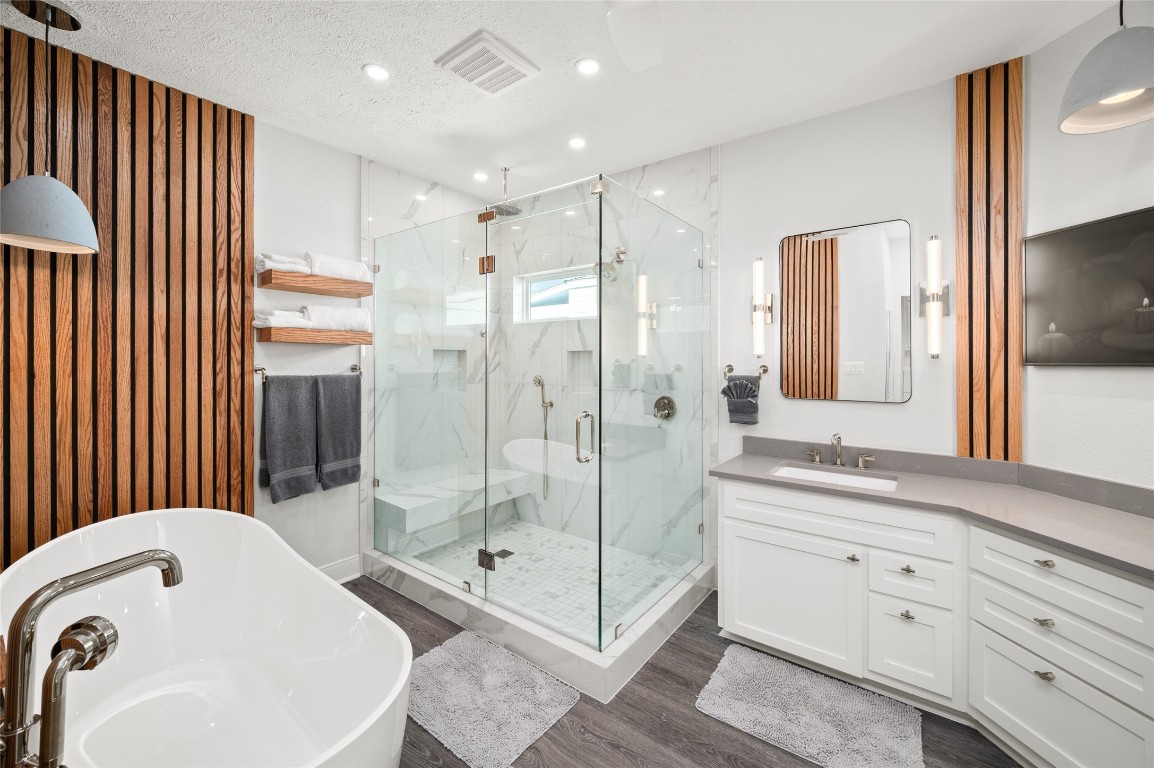 242 Isles End Road Tiki Island, TX 77554 - Photo 20 of 50 The Primary Suite bath is a spa retreat in itself! Renovated in 2025, this bathroom features an oversized soaking tub, two person shower with three shower heads, shower bench, and double sink vanity with frame TV.