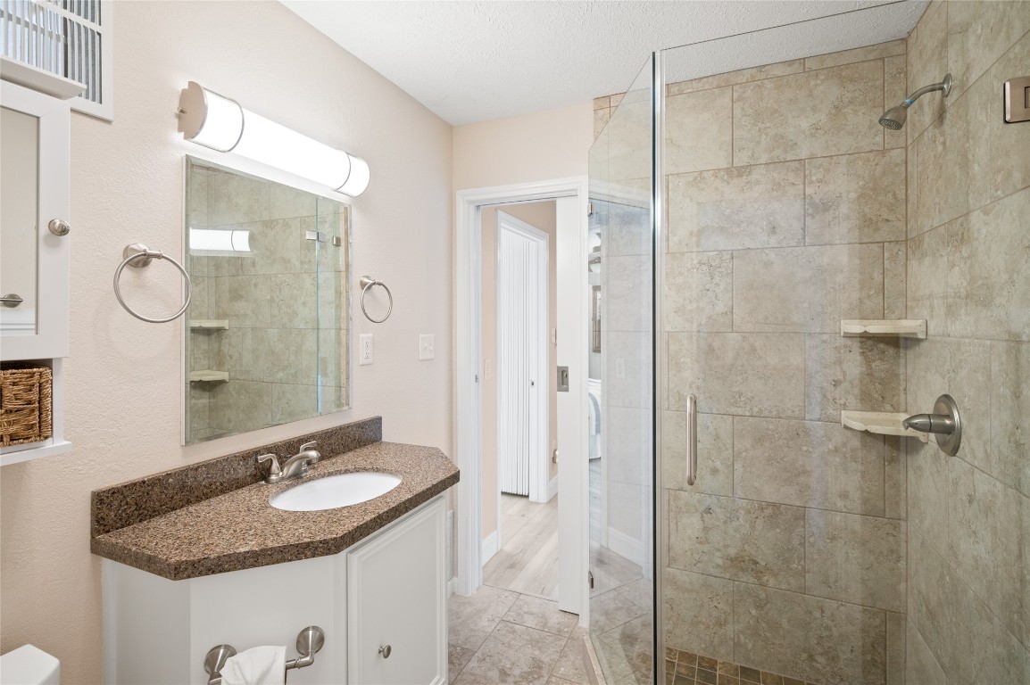 242 Isles End Road Tiki Island, TX 77554 - Photo 28 of 50 The Hollywood bath between the secondary bedrooms and bunk room features a standing glass enclosed shower with stone.