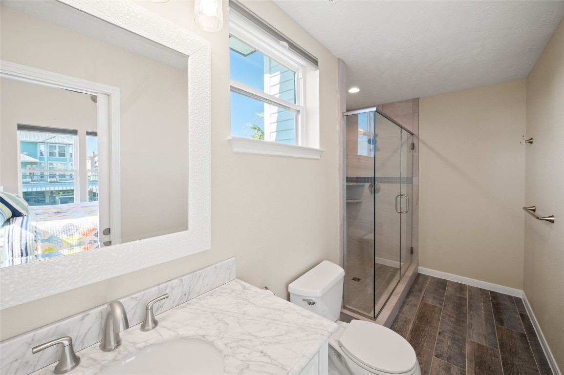 242 Isles End Road Tiki Island, TX 77554 - Photo 34 of 50 Secondary en-suite bathroom with marble countertops and a standing glass shower.