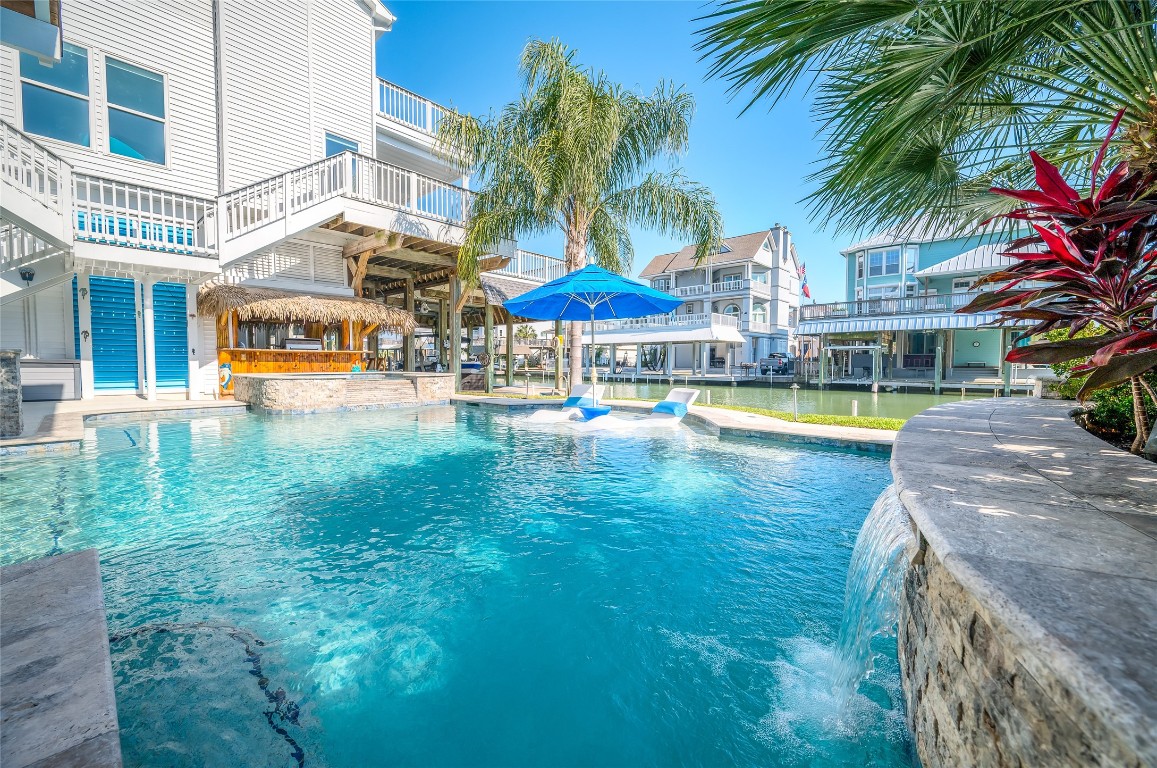 242 Isles End Road Tiki Island, TX 77554 - Photo 36 of 50 This close up image of the pool highlights the water feature to the right and the view of the canal just beyond the pool.