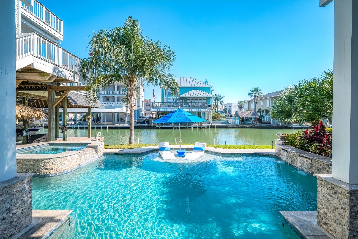 242 Isles End Road Tiki Island, TX 77554 - Photo 38 of 50 Mature landscape surrounds the pool. At night, the landscape lighting highlights the lush greenery and pool. While the two fire bowls around the end of the pool provide an element of movement and comfort.