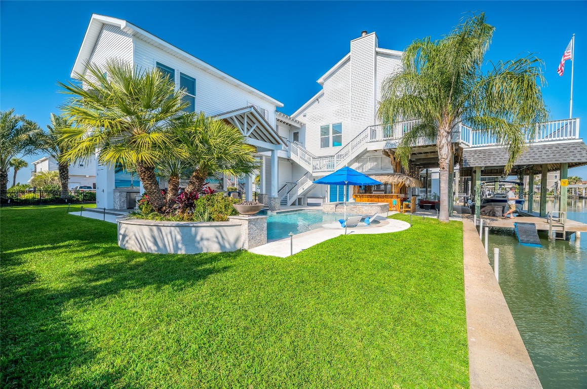 242 Isles End Road Tiki Island, TX 77554 - Photo 42 of 50 The side elevation of the home showcases the meticulously landscaped yard with four large medjool palm trees, lemon tree, landscape lights and two fire bowls.