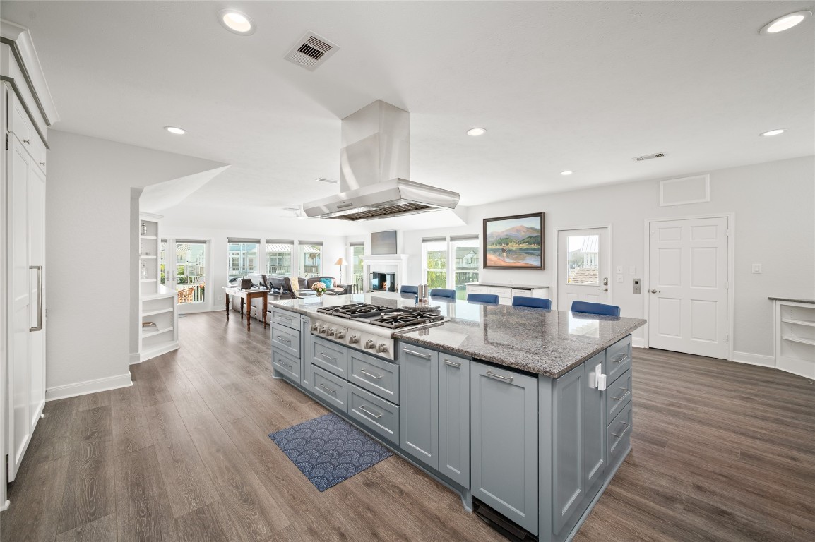 242 Isles End Road Tiki Island, TX 77554 - Photo 7 of 50 The kitchen flows effortlessly into the spacious living and dining areas, anchored by a fireplace and surrounded by windows capturing views of the canal and bay. Beautiful and durable luxury vinyl flooring runs throughout the home, complementing the bright coastal aesthetic and providing easy maintenance.