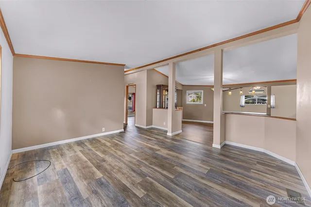 a view of an empty room with window and wooden floor