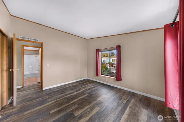 a view of an empty room with window and wooden floor