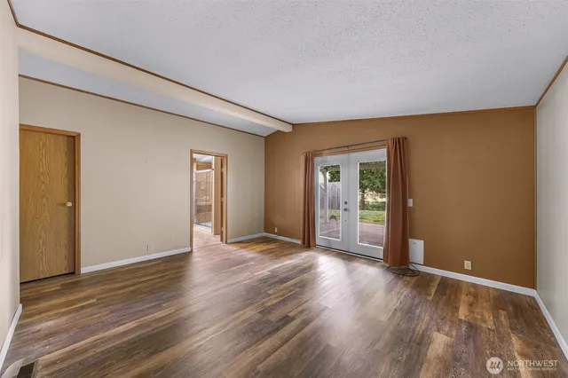 a view of an empty room with wooden floor and closet