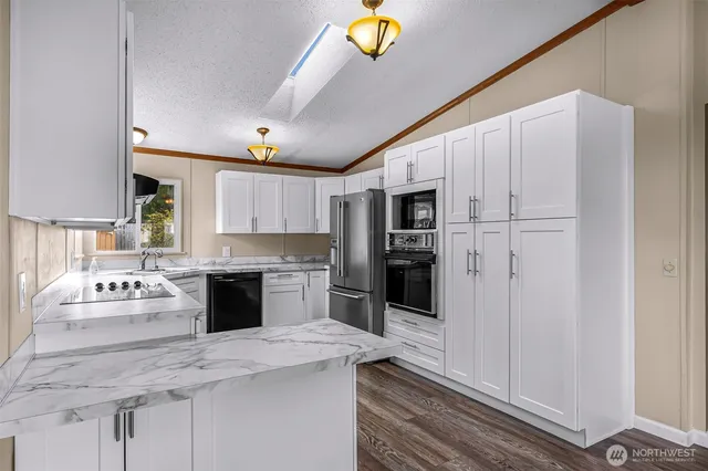 a large white kitchen with a stove a sink dishwasher and a refrigerator with wooden floor