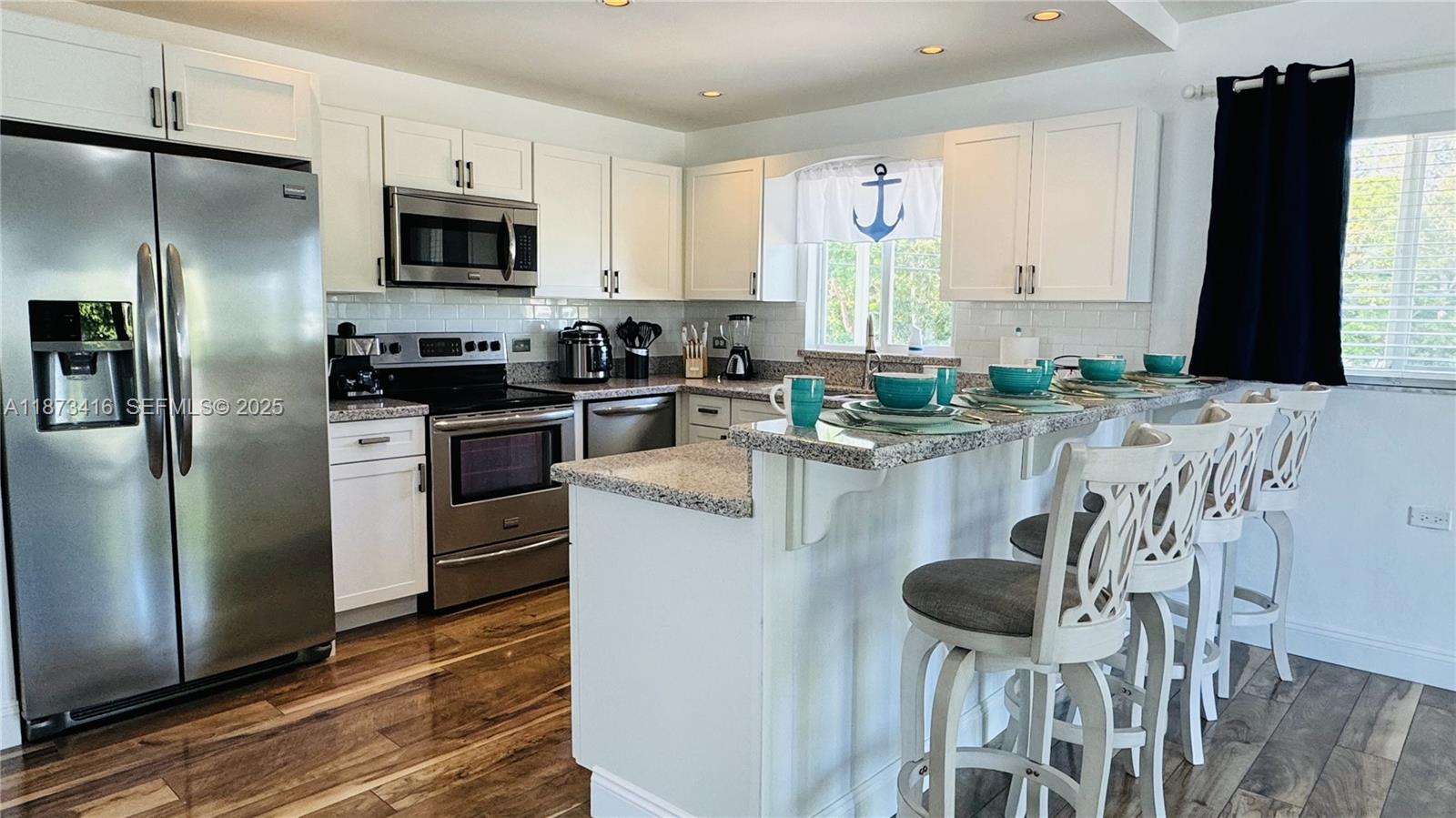 443 4th Road, Unit MAIN Key Largo, FL 33037 - Photo 4 of 31 a kitchen with stainless steel appliances granite countertop a stove a sink a microwave a refrigerator and white cabinets