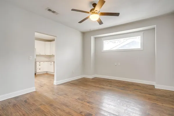an empty room with wooden floor a ceiling fan and closet area