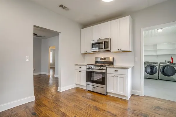a kitchen with granite countertop white cabinets and white appliances