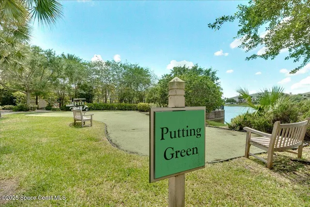 a sign board with a house in the background