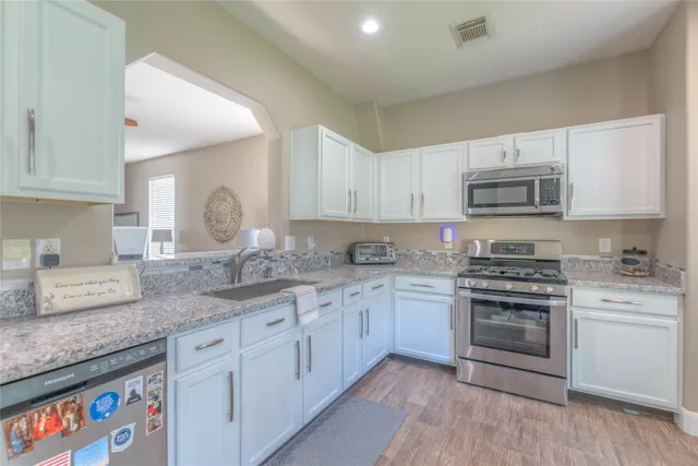 a kitchen with granite countertop white cabinets and stainless steel appliances