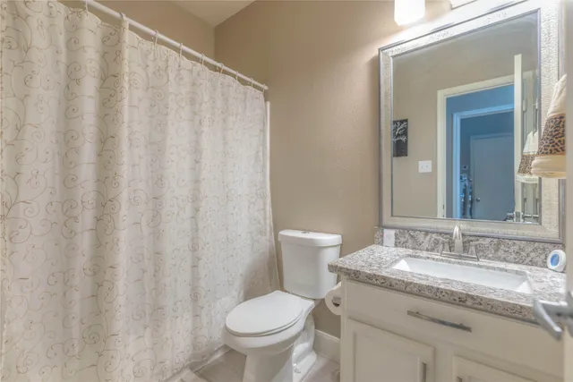 a bathroom with a granite countertop sink and a toilet