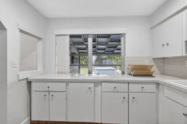 a kitchen with white cabinets and window