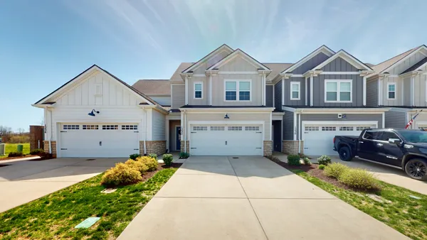 a view of a white house next to a yard with potted plants