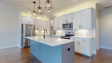 a view of a kitchen with stainless steel appliances granite countertop a refrigerator a sink a stove and a wooden floors