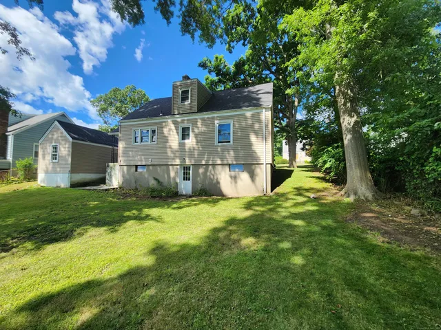 a view of a house with a big yard and large trees