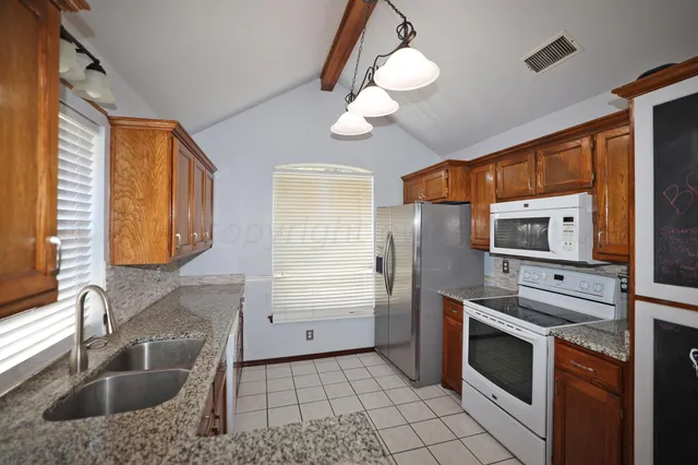 a kitchen with stainless steel appliances granite countertop a sink and a stove next to a window